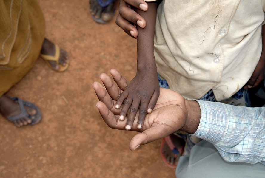 Child's hand on top of doctor's hand